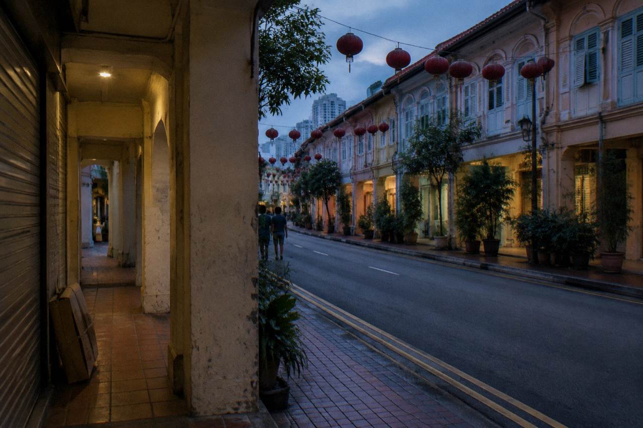 Shophouse facades and lanterns along a Chinatown street in Singapore at dusk