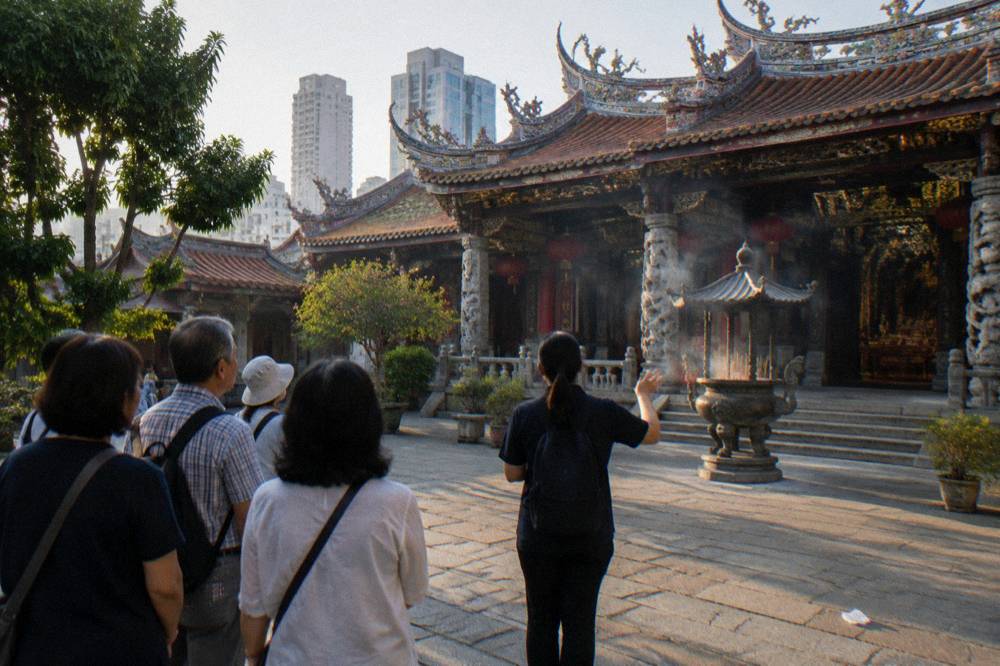 A tour guide speaking to a small group of visitors on a historic street in Singapore.