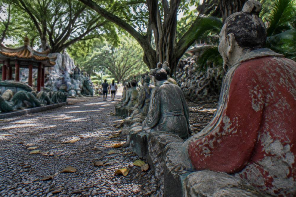 Shaded walkway in a Singapore park with stone figures along the edge