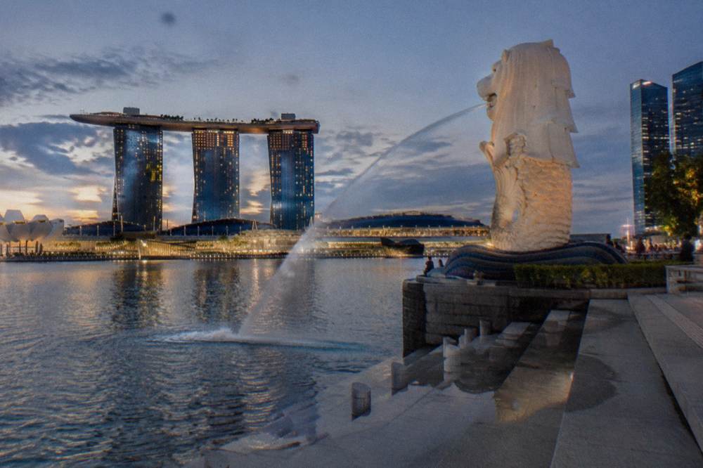Evening view across the bay with the lit towers and the free public promenade in the foreground
