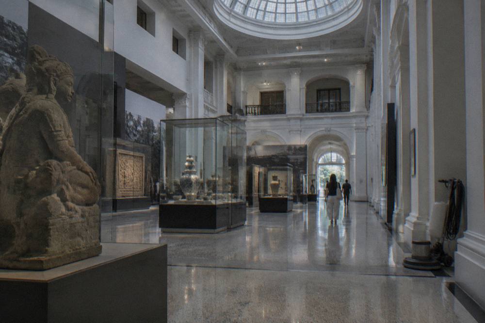 Museum gallery hall with display cases and a high ceiling.