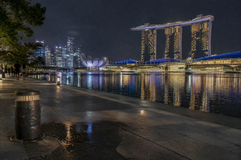Night skyline across a bay with illuminated towers and reflections on calm water