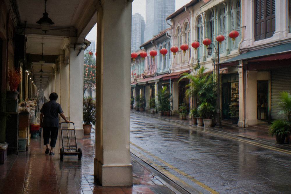 Shophouses along a Chinatown street with lanterns strung overhead in daylight