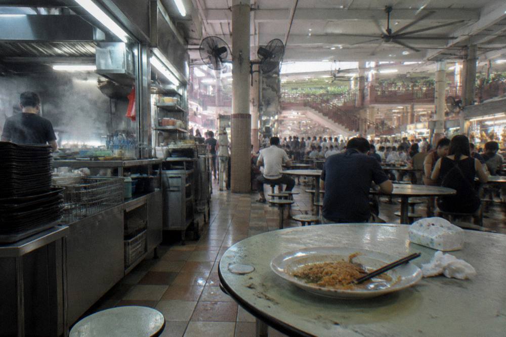 Hawker centre stalls with food vendors and shared seating tables