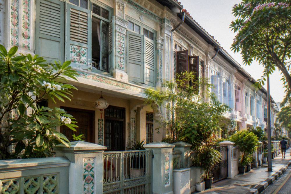 A heritage shophouse facade with wooden shutters and hanging lanterns