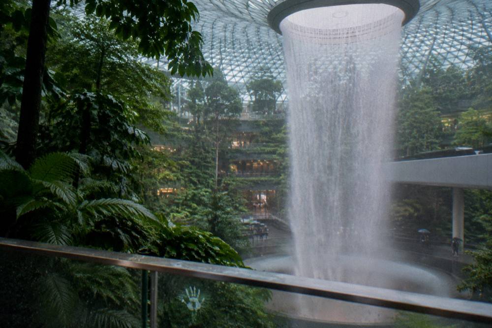 Indoor waterfall falling through a multi-storey glass atrium surrounded by plants