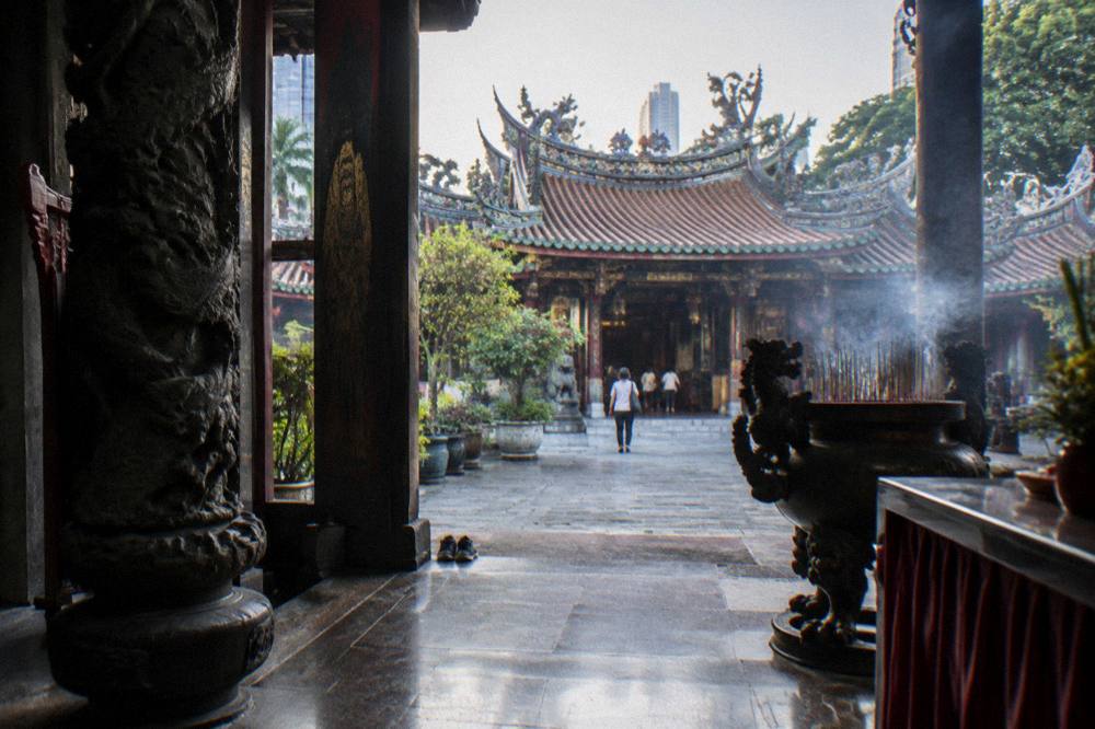 A temple entrance with ornate roof decoration and stone lanterns