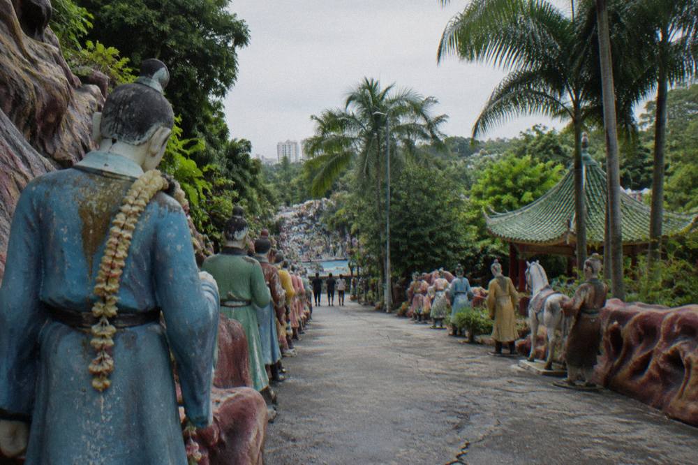 Rows of painted statues depicting figures from Chinese folklore arranged along a garden path