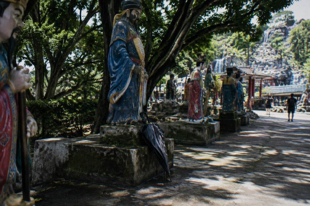 Statues of mythological figures standing on a shaded terrace within the park grounds