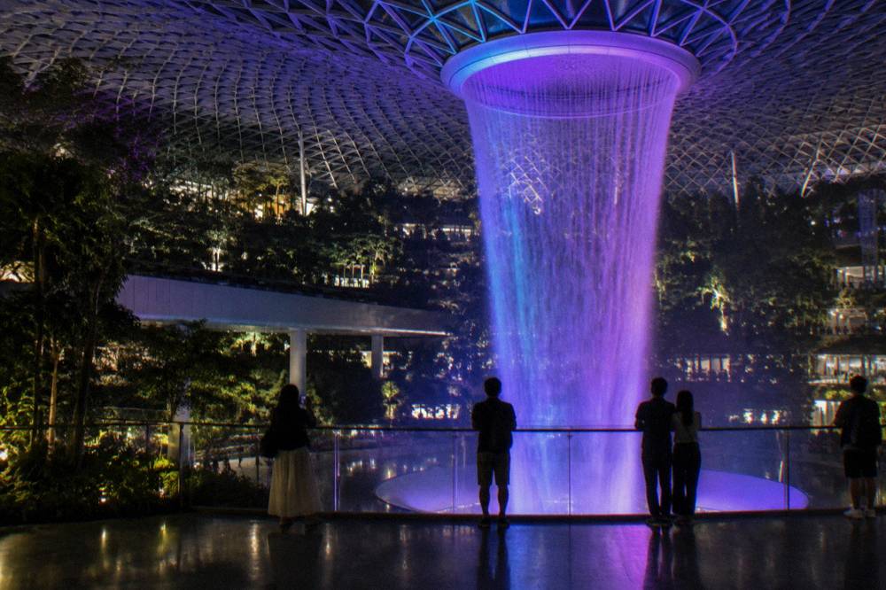 The Rain Vortex waterfall at night, lit for the light and music showcase at Jewel Changi Airport