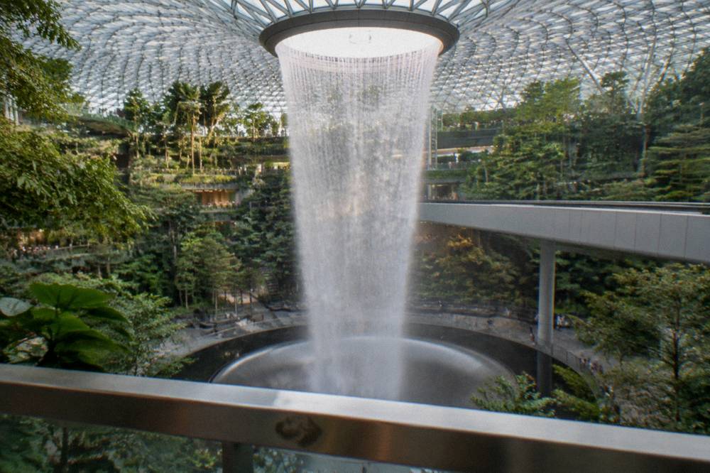 The open atrium of Jewel Changi Airport seen from a garden level, with the Rain Vortex in the centre