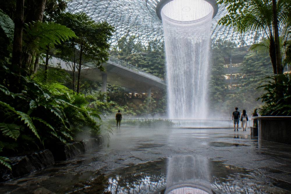 Water falling through the glass atrium of Jewel Changi Airport into the indoor garden below