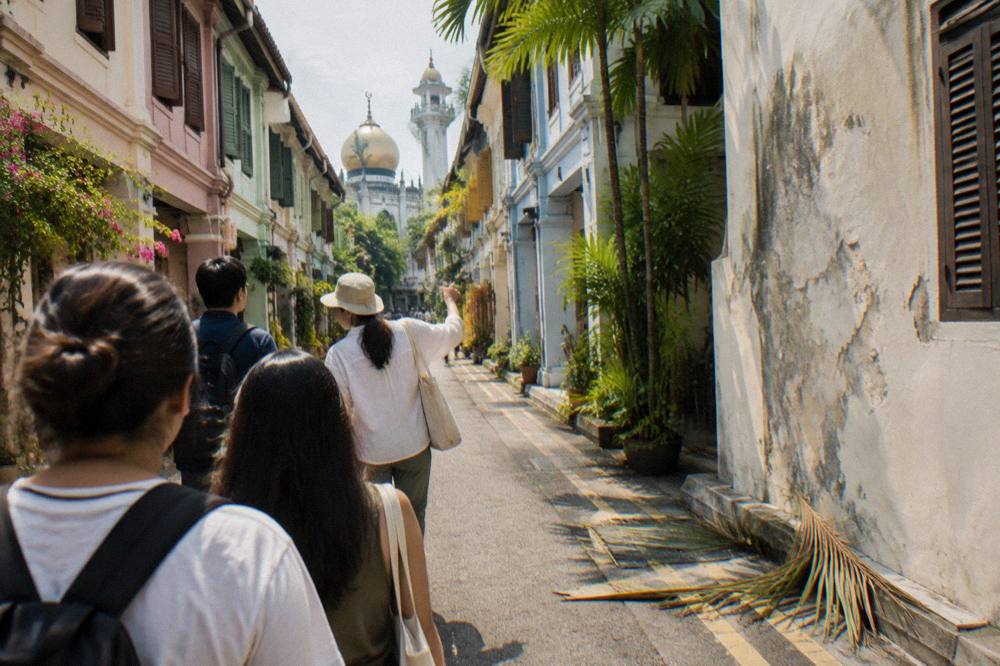 Walking guide leading a small group along a shophouse street in a heritage district