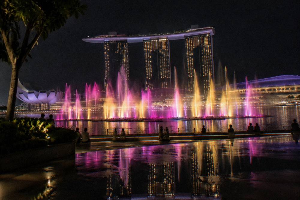 Water jets lit by coloured lights in front of the towers during an evening show