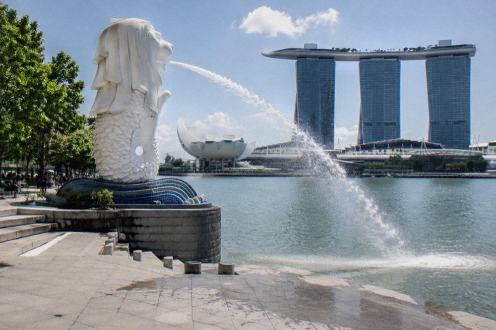 Merlion statue spraying water into Marina Bay with the skyline behind it