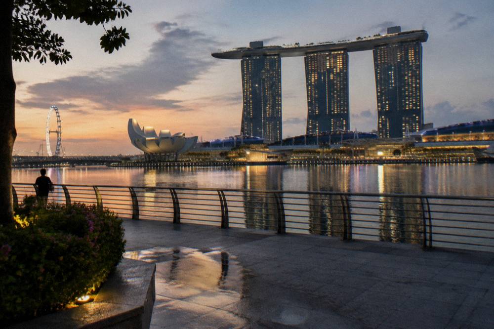 Waterfront viewing deck at dusk with city lights reflecting on the bay water
