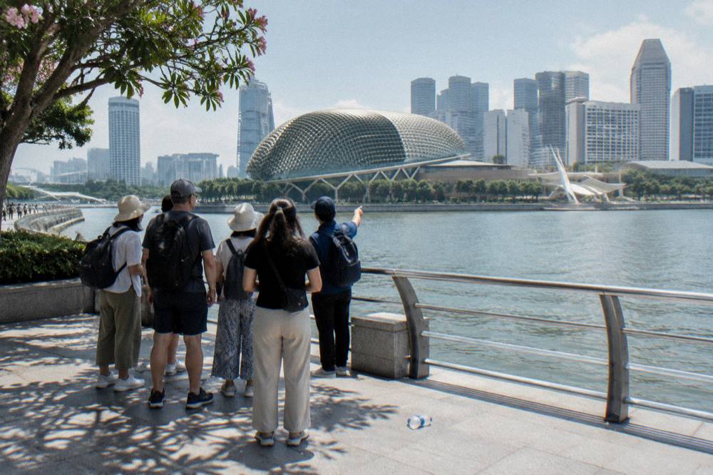 Group of walkers with a guide on a waterfront promenade beside a bay