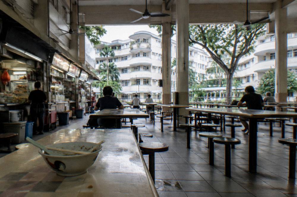 Long shared tables with ceiling fans above a hawker centre floor