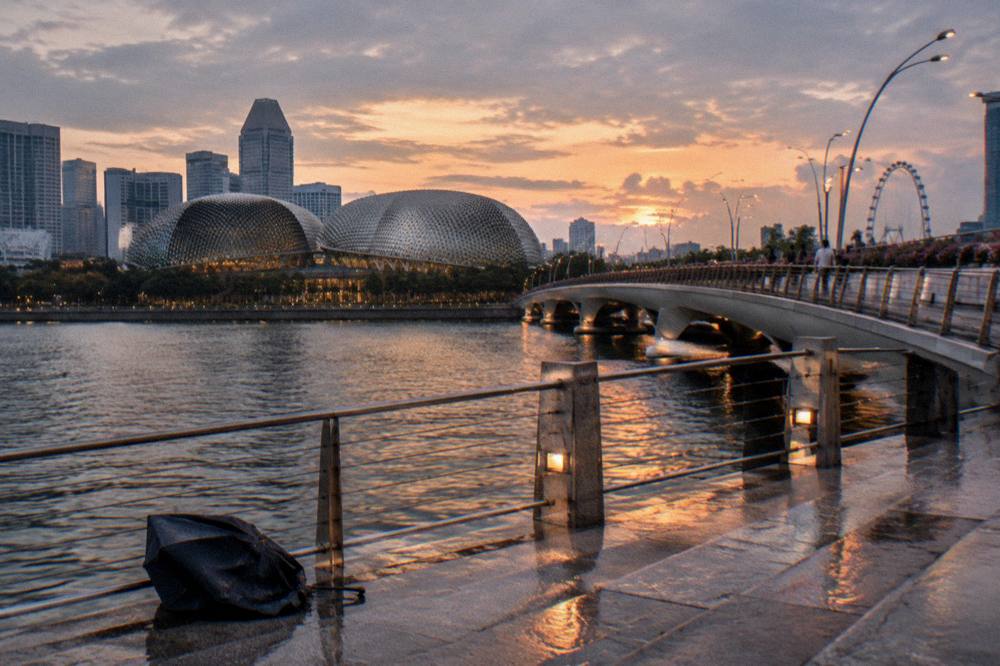 A curved bridge and waterfront promenade beside a bay at dusk